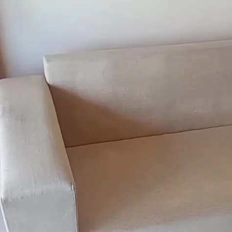 Sofá claro depois da higienização, numa sala de piso branco